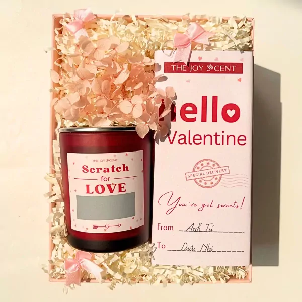Valentine gift set with red candle, pink flowers, and "Hello Valentine" card.