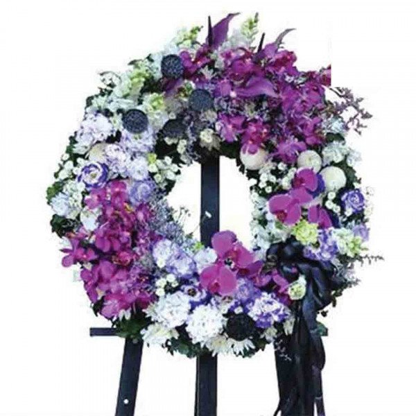 Purple and white floral wreath with orchids on a black easel.