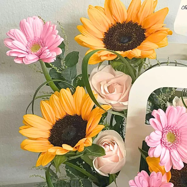 A bouquet with sunflowers, pink gerbera daisies, and light pink roses.
