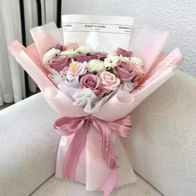 Subtle Pink Bouquet with roses, daisies, and a pink ribbon on a couch.