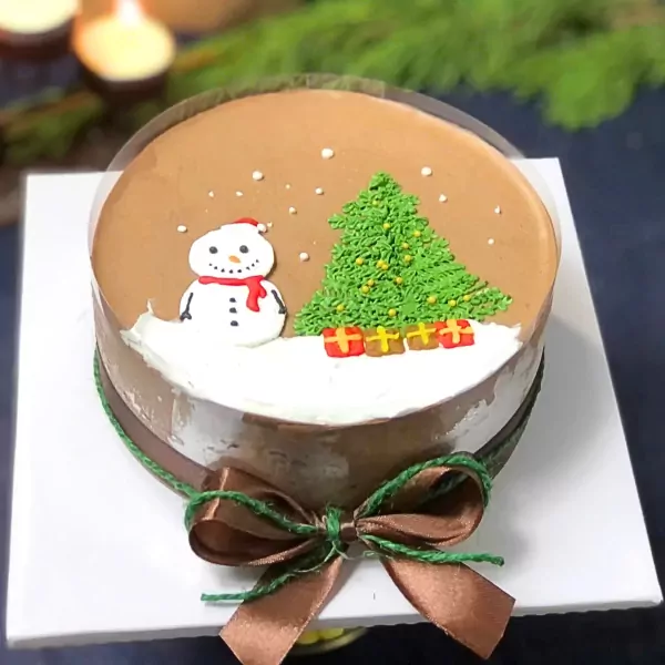 Chocolate mousse cake with snowman, Christmas tree, presents, and a satin ribbon bow.