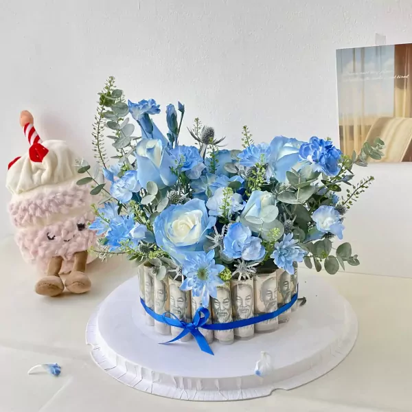 Blue floral money cake with a plush cupcake toy.