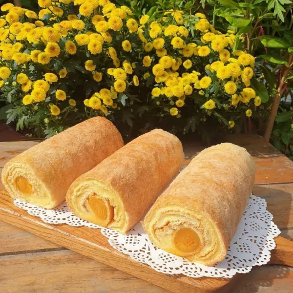 Three golden egg floss rolls with cheese filling on a wooden board.