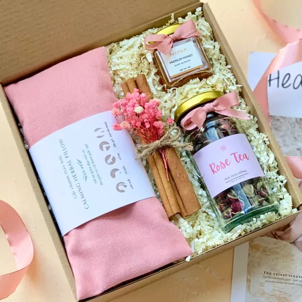 Gift set with pink herbal pillow, rose tea, cinnamon sticks, dried flowers, and honey jar.