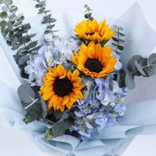 Bouquet of sunflowers and blue hydrangeas with eucalyptus leaves.