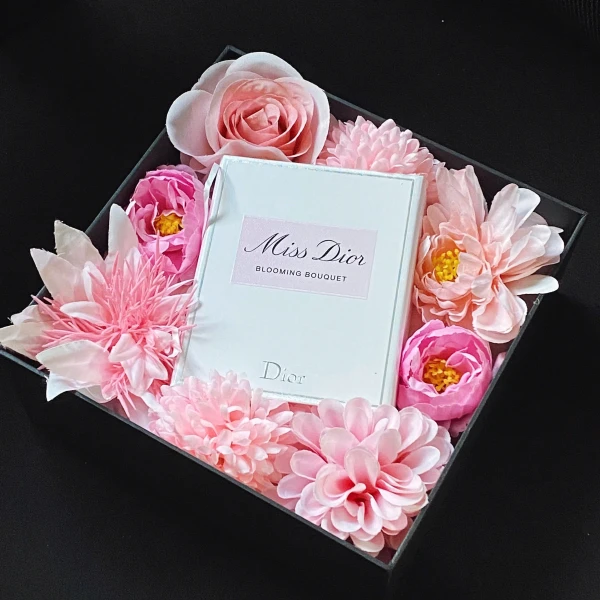 Dior Miss Blooming Bouquet EDT perfume box surrounded by pink artificial flowers.