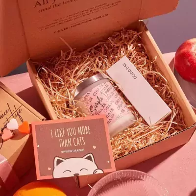 Gift box with scented candle, card that says "I like you more than cats", and a red apple.