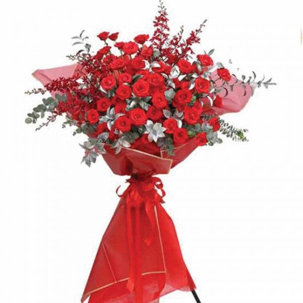 Grand bouquet of red roses and red orchid sprigs on a stand with red fabric.