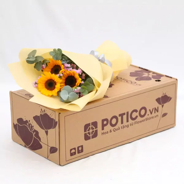 Bouquet of sunflowers with eucalyptus leaves, gift-wrapped in yellow paper, on top of a cardboard box.