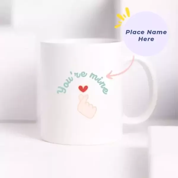 White ceramic mug with "You're mine" design and a heart hand gesture.