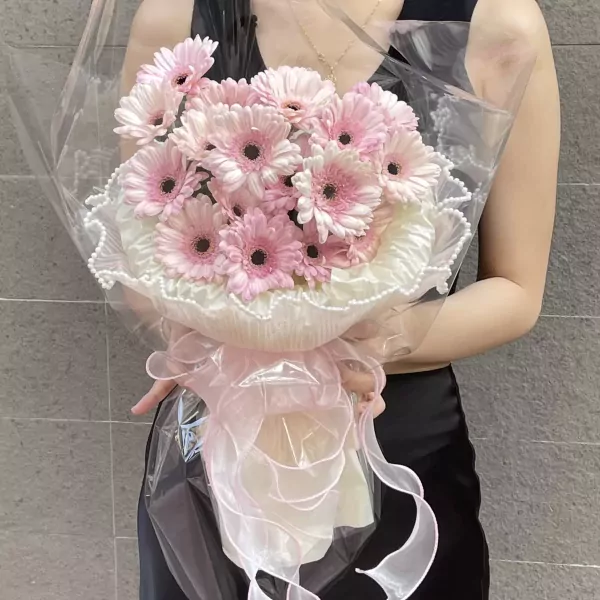 Pink gerbera daisy bouquet wrapped in clear plastic with pink ribbon.
