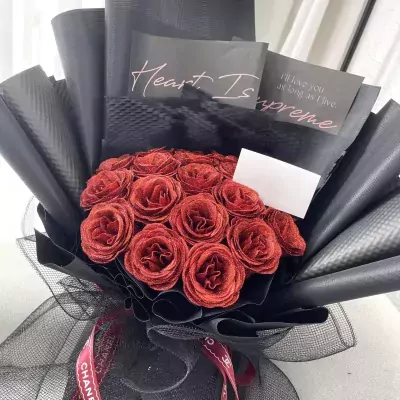 Sparkling ruby roses in a black bouquet with a Chanel ribbon.
