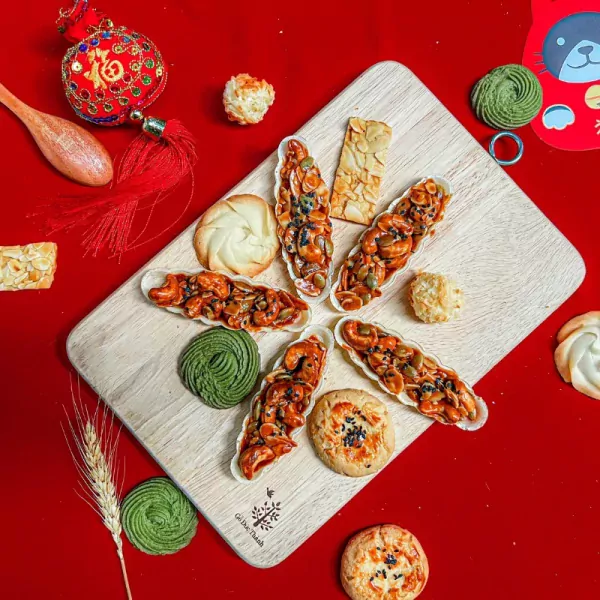 Assortment of Vietnamese Tet cookies, nuts, and treats on a wooden board.