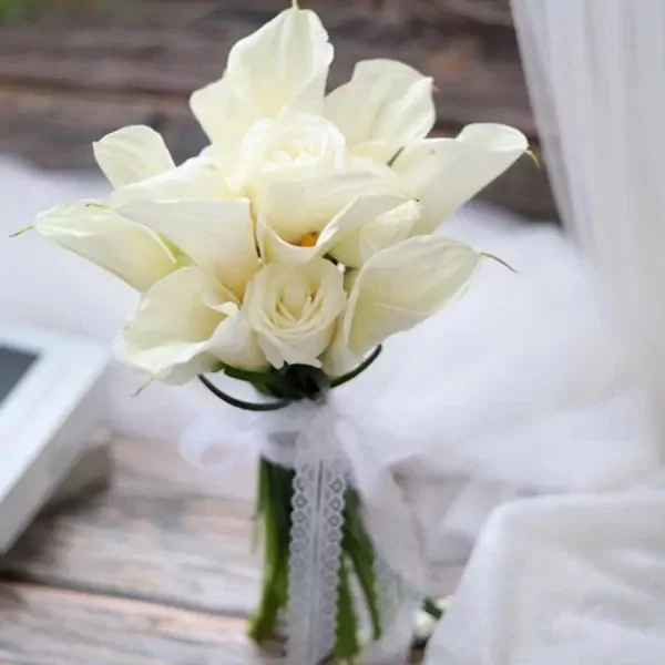 White calla lilies and roses bouquet tied with white lace ribbon.