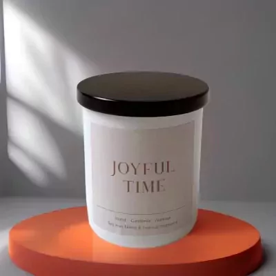 A white candle with "JOYFUL TIME" printed on it, on an orange pedestal.