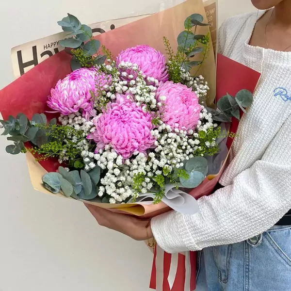 Pink peonies and baby's breath in a bouquet with eucalyptus leaves.