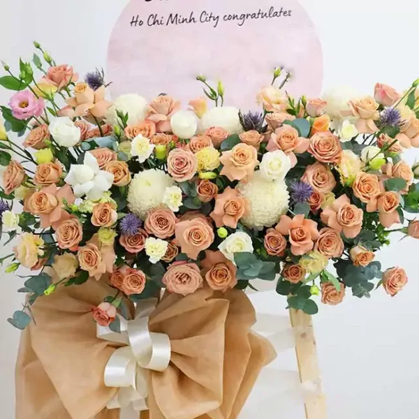 Elegant floral arrangement with pink, peach, and white roses, white chrysanthemums, and greenery.
