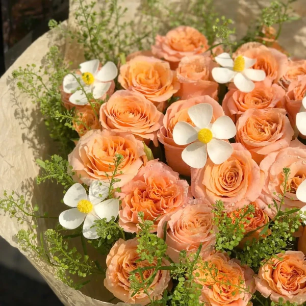 A bouquet of peach roses with delicate white flowers and greenery.