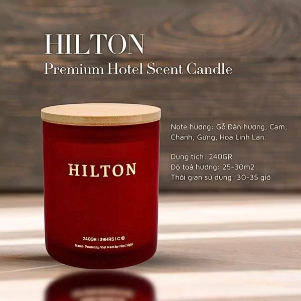 Hilton Premium Hotel Scent Candle in a red glass jar with a wooden lid.