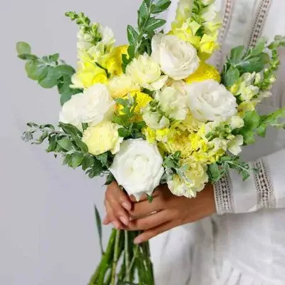 Bridal bouquet with white roses, yellow snapdragons, and yellow chrysanthemums.