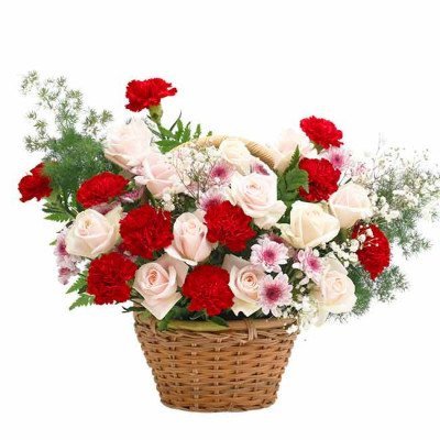 A woven basket filled with red carnations, cream roses, and baby's breath.