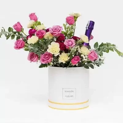 Flower box with pink roses, white flowers, and a purple wine bottle.