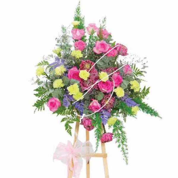Standing floral arrangement with pink roses, pink lotus flowers, and green carnations.