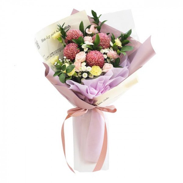 Bouquet of pink chrysanthemums, cream roses, yellow carnations, and greenery in purple and cream paper.