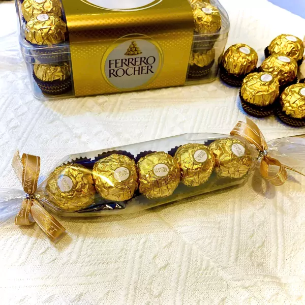 Ferrero Rocher chocolates in gift packaging, with a box of chocolates in the background.