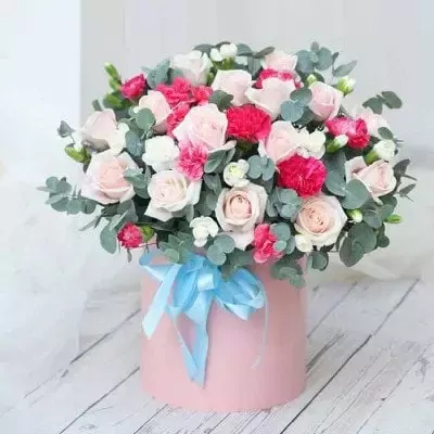Pink box of roses, carnations, and eucalyptus with blue ribbon.