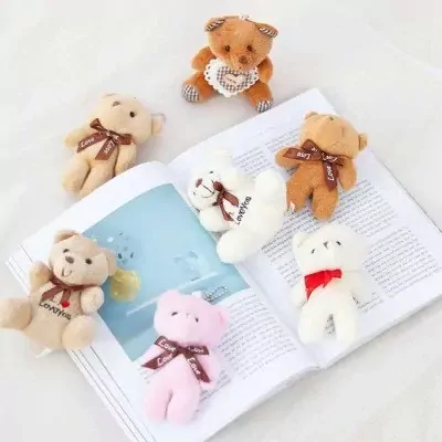 Seven small teddy bears, including pink, white, and brown, are scattered on an open book.