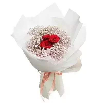 A bouquet of red roses and baby's breath, wrapped in white paper and tied with a pink ribbon.