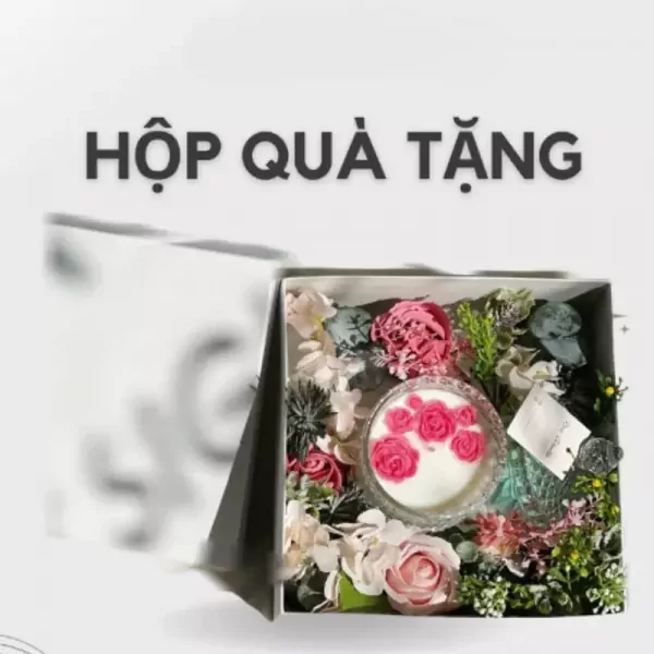 Gift box with scented candle decorated with pink roses and wax flowers.