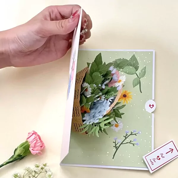 A hand opens a pop-up card showing a vibrant bouquet of flowers.