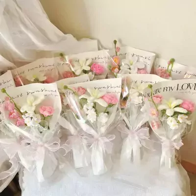 Crocheted flower bouquets wrapped in clear cellophane with pink bows and inscribed messages.