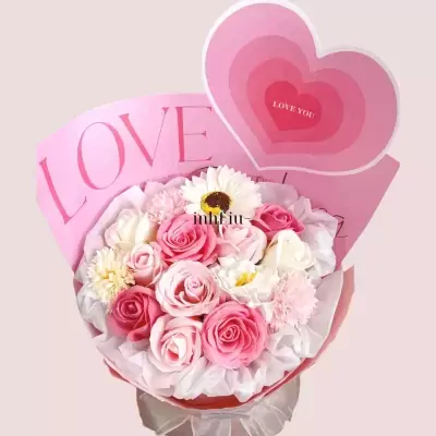 Pink roses and white daisies in a bouquet with a "LOVE" banner and a heart decoration.