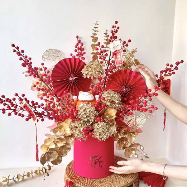 Lucky cat with red berries, gold leaves and fans in a pink box.