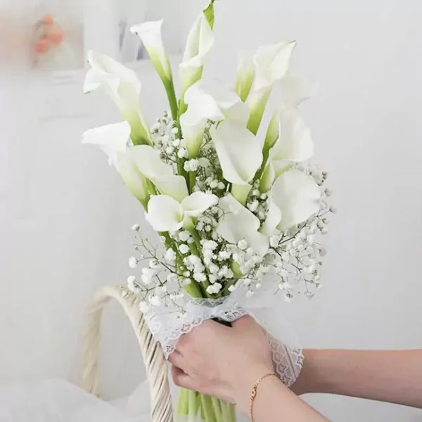 White calla lily bouquet with baby's breath, tied with lace, held by hands.