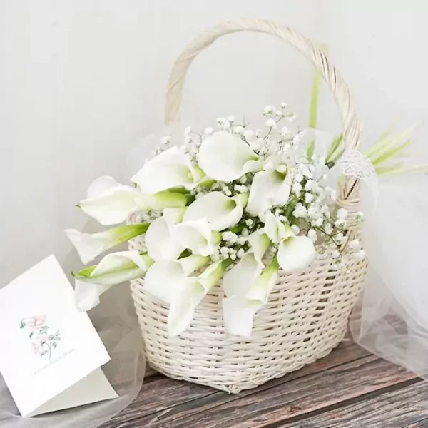 White calla lily and baby's breath bouquet in a white wicker basket with a wedding card.