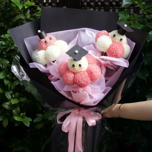 Graduation-themed bouquet of pink and white pingpong chrysanthemums with graduation caps.