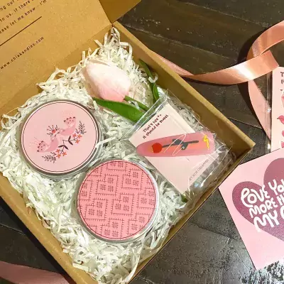 Pink gift box with scented candles, a tulip, and a hair clip.