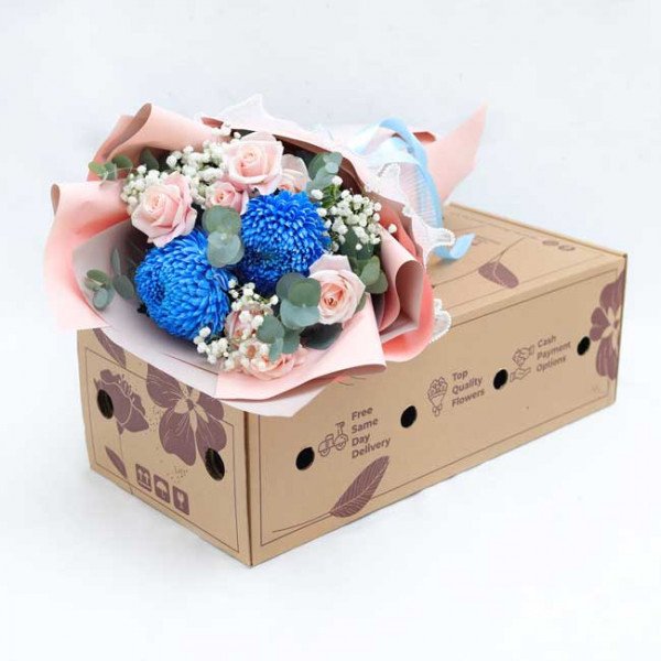 Bouquet of blue chrysanthemums and pink roses in a cardboard box, tied with ribbon.