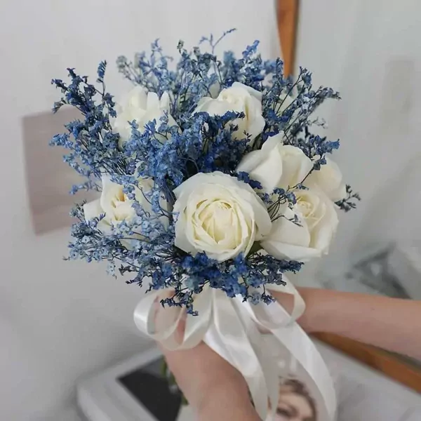 White roses and blue flowers with a white ribbon.