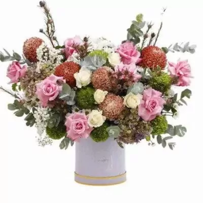A large floral arrangement in a lilac box with roses, chrysanthemums, and greenery.