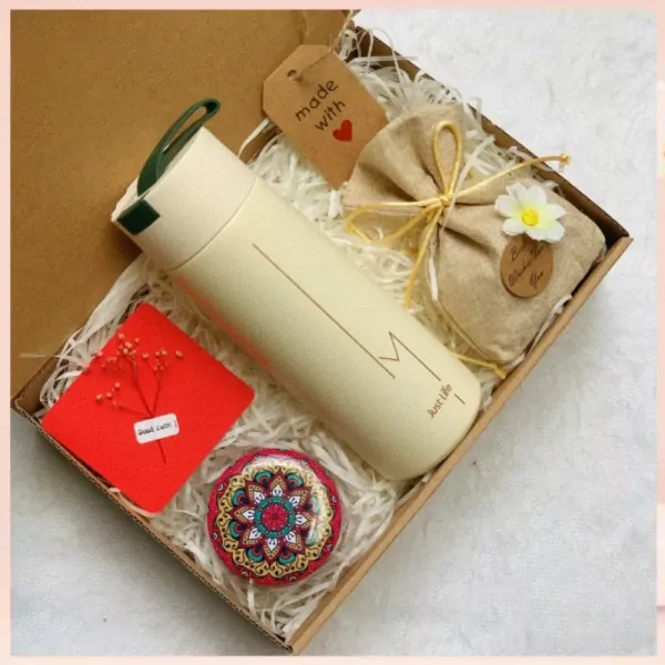 Gift box with a tumbler, scented candle, notebook, and small trinket.
