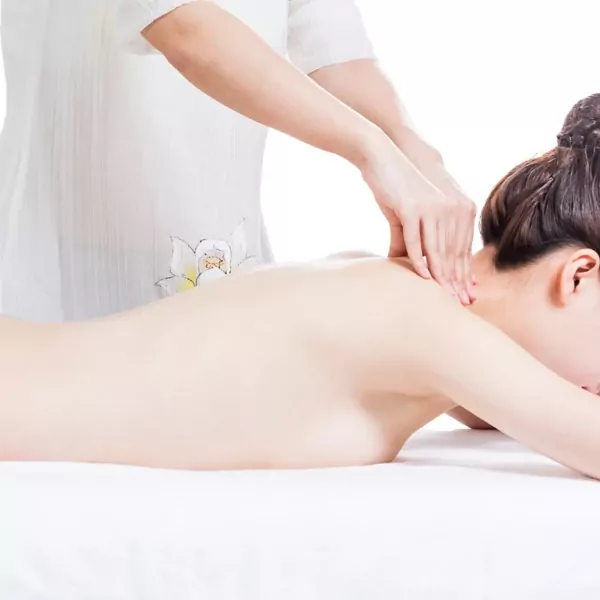 Woman receiving a neck and shoulder massage on a white massage table.
