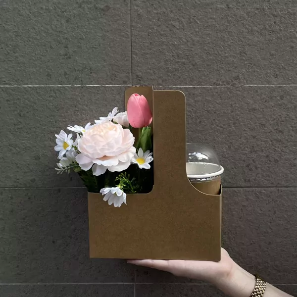 Brown cardboard caddy with pink tulip, peach peony, and daisies next to a covered cup.