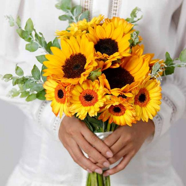 Bridal bouquet of sunflowers and gerbera daisies with greenery.