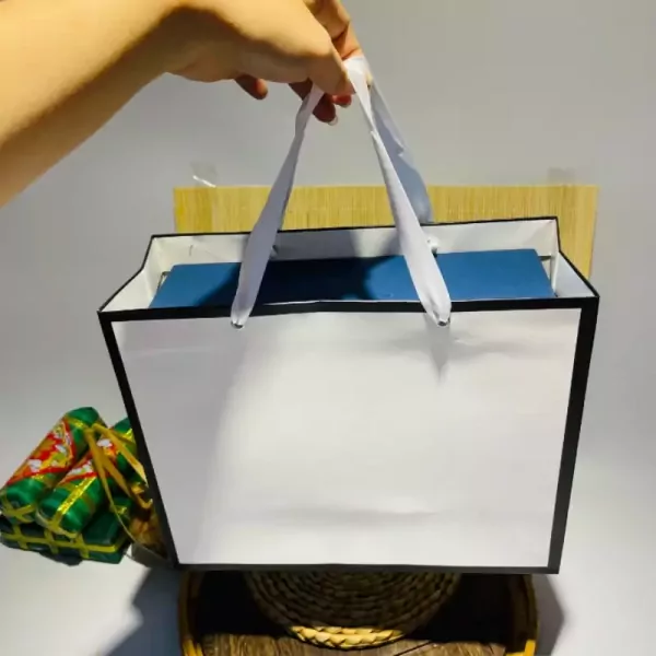 White gift bag with white handles, a blue item inside, and decorative items on the side.