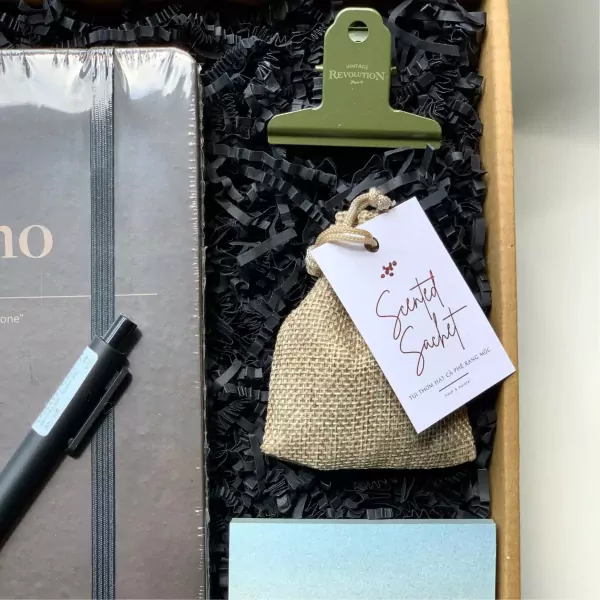 Gift set with notebook, pen, clip, and coffee-scented sachet in black packaging.